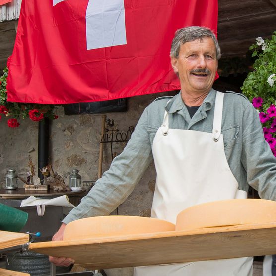 Foto Der Alpkäse wird zum Ausliefern auf Holzbrettern aus dem Keller getragen - zum Foto