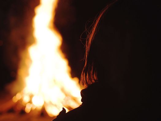 Foto Person sitzt am nächtlichen Lagerfeuer - zum Foto