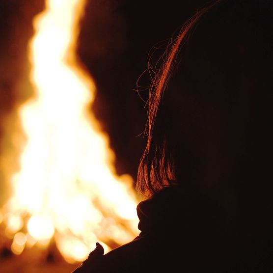 Foto Person sitzt am nächtlichen Lagerfeuer - zum Foto