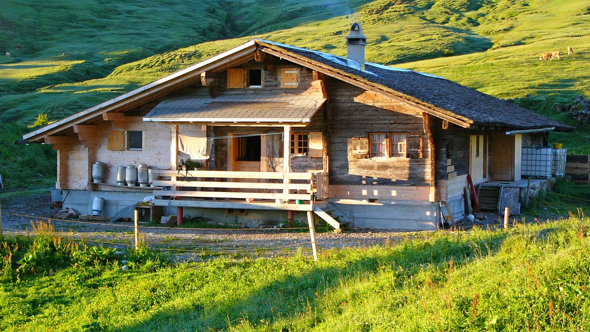 Traditionelle Alphütte in der Morgensonne mit rauchendem Kamin