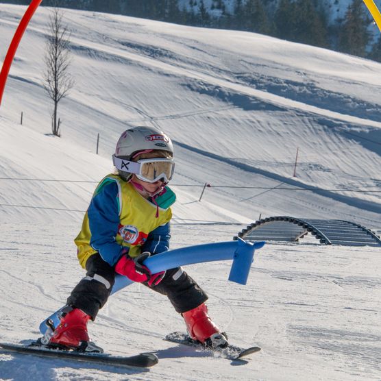 Foto Kind fährt mit Skis unter Torbogen hindurch - zum Foto