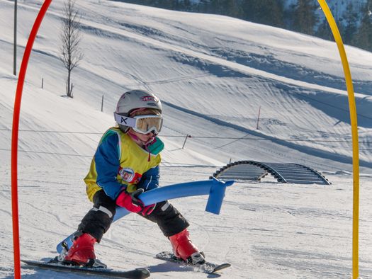 Foto Kind fährt mit Skis unter Torbogen hindurch - zum Foto