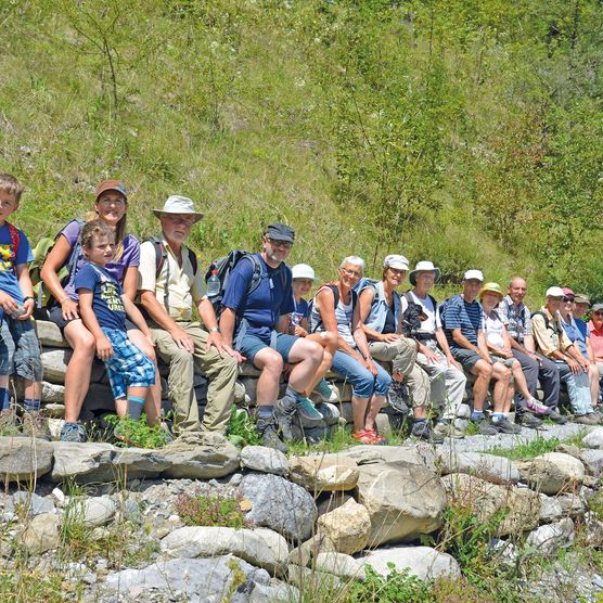 Foto Die Exkursionsteilnehmer sitzen auf einer Trockensteinmauer - zum Foto